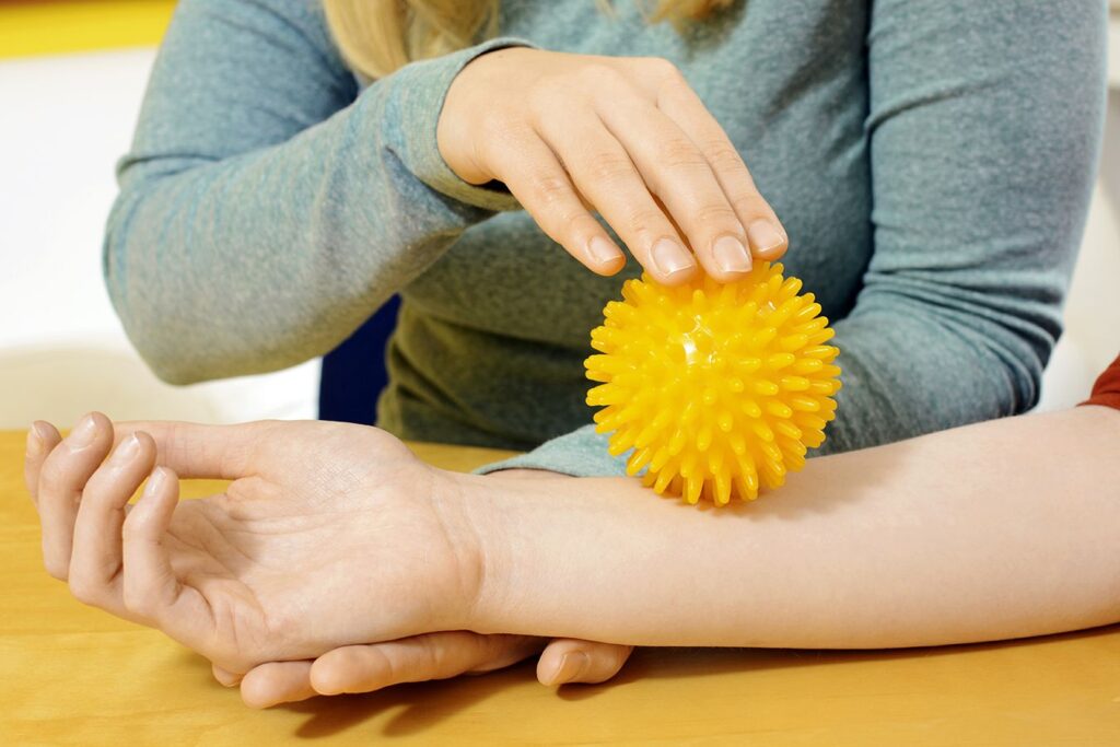 Ergotherapie Handtherapie mit gelbem Igelball zur sensorischen Stimulation und Verbesserung der Handmotorik