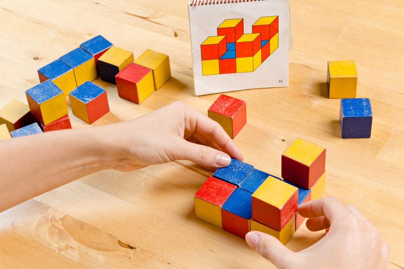 Ergotherapeutische Übung mit bunten Holzbausteinen zur Förderung von Kognition, räumlichem Denken und Feinmotorik